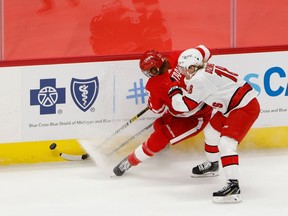 Jan 14, 2021; Detroit, Michigan, USA;  Detroit Red Wings defenseman Marc Staal (18) and Carolina Hurricanes center Ryan Dzingel (18) battle for the puck in the third period at Little Caesars Arena.