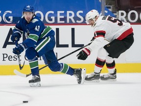 Canucks defenceman Quinn Hughes dishes off a backhand pass to a teammate while Ottawa Senators forward Artem Anisimov gives chase during the Canucks-Senators NHL game at Rogers Arena on Monday.