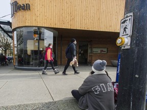 A panhandler sits outside the JJ Bean Coffee Roasters location at East 14th and Main Street in Vancouver.