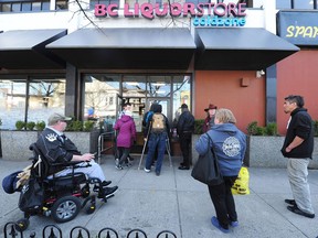 Customers line up before opening time at the BC Liquor Store on Commercial Dr. in Vancouver, BC., March 19, 2020.