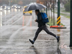 A pedestrian tries to leap over a giant puddle while crossing a street in Vancouver, BC.