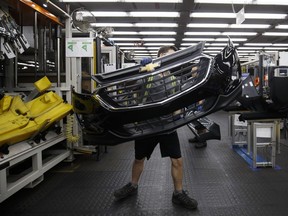 An employee carries auto parts at a Magna facility in Guelph, Ont., in 2018.