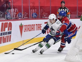 Canucks rookie winger Nils Hoglander shields the puck from a pursuing Nick Suzuki of the Montreal Canadiens during their Feb. 2, 2021 NHL game at the Bell Centre in Montreal.