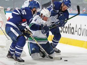 Canucks winger J.T. Miller squeezes between Toronto Maple Leafs Alex Kerfoot (left) and Morgan Rielly in a battle for the puck during their Feb. 4, 2021 NHL game at Scotiabank Arena in Toronto.