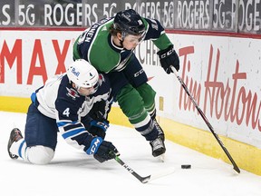 Vancouver Canucks forward Jake Virtanen battles with Winnipeg Jets defenceman Neal Pionk in the second period at Rogers Arena Friday night.