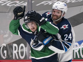 Nils Hoglander of the Vancouver Canucks reacts after getting grabbed by Derek Forbort of the Winnipeg Jets during NHL hockey action at Rogers Arena on Friday.