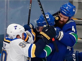 Ryan O'Reilly, left, of the St. Louis Blues jostles with Oscar Fantenberg, centre, and Jordie Benn of the Vancouver Canucks in Game 4 of the Western Conference first round during the 2020 NHL playoffs at Rogers Place on Aug. 16, 2020. in Edmonton.