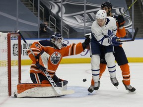 Toronto Maple Leafs' Zach Hyman (11) battles the Edmonton Oilers' Darnell Nurse (25) in front of goalie Mike Smith (41) at Rogers Place in Edmonton on Saturday, Feb. 27, 2021.