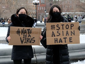 Protestors hold signs at the End The Violence Towards Asians rally in Washington Square Park on February 20, 2021 in New York.