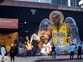 People stop by a mural of late Kobe Bryant, who perished one year ago alongside his daughter and seven others when their helicopter crashed into a hillside, in Los Angeles, Calif., Jan. 26, 2021.