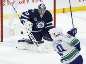 Winnipeg Jets goalie Connor Hellebuyck stops a blast from Canucks centre Elias Pettersson during their Jan. 30, 2021 NHL game in Winnipeg.