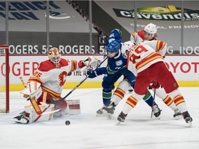 Calgary Flames defenceman Juuso Valimaki (6) and defenseman Nikita Nesterov (89) check Vancouver Canucks forward Tanner Pearson (70) as goalie Jacob Markstrom (25) makes a save in the first period at Rogers Arena.