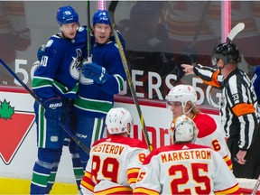 Vancouver Canucks Brock Boeser, with Elias Pettersson (far left)  looks to Calgary Flames goalie Jacob Markstrom after Boeser scored the lone Canucks goal.