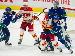 Vancouver Canucks' Quinn Hughes and Calgary Flames' Mikael Backlund battle in front of goalie Thatcher Demko while Canucks' Adam Gaudette moves toward Flames' Milan Lucic during NHL action at Rogers Arena in Vancouver on Feb. 11.