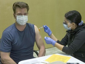 Chris Nelson, a PE and law teacher at Panorama Ridge Secondary School, gets his COVID-19 vaccine from Fraser Health licensed practical nurse Amrit Parhar in Surrey on March 24.