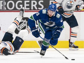 VANCOUVER, BC - MARCH 13: Quinn Hughes #43 of the Vancouver Canucks skates with the puck against Leon Draisaitl #29 of the Edmonton Oilers during the second period of NHL action at Rogers Arena on March 13, 2021 in Vancouver, Canada.