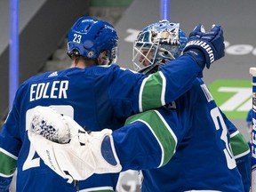 VANCOUVER, BC - MARCH 13: Goalie Thatcher Demko #35 of the Vancouver Canucks is congratulated by teammate Alex Edler #23 after defeating the Edmonton Oilers 2-1 in NHL action at Rogers Arena on March 13, 2021 in Vancouver, Canada.