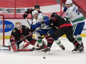 Vancouver Canucks centre Zack MacEwen (71) is taken off the puck by Ottawa Senators defenceman Artem Zub (2) as they battle in front of goalie Joey Daccord (34) in the first period at the Canadian Tire Centre.