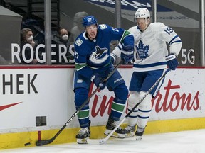 Canucks defenceman Travis Harmonic, looking up ice with the puck near his stick as Maple Leafs centre Jason Spezza closes on him, has built a strong pairing with young star Quinn Hughes of late.