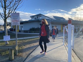 Some teachers and staff at École Woodward Hill Elementary School in Surrey on Feb. 23, 2021, after seven schools in the Fraser Health region reported exposures to a COVID-19 variant.