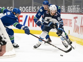 Kyle Connor (81) of the Winnipeg Jets controls the puck against Jordie Benn (8) and Tyler Myers (57) of the Vancouver Canucks during the first period of NHL action at Rogers Arena on March 22 in Vancouver. Myers, a former Jet, is among the 20-plus players and coaches on the COVID-alert list in Vancouver.