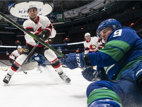 J.T. Miller of the Vancouver Canucks falls while battling for the puck with Artem Zub of the Ottawa Senators during the first period of NHL action at Rogers Arena on April 22, 2021 in Vancouver, Canada.
