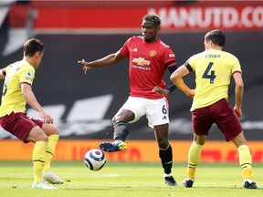 Paul Pogba of Manchester United is challenged by Ashley Westwood of Burnley and Jack Cork of Burnley during the Premier League match between Manchester United and Burnley at Old Trafford on April 18, 2021 in Manchester, England.