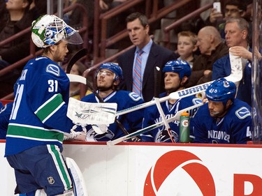 Goalie Eddie Lack gets a stick from equipment manager Pat O'Neill while relieving Roberto Luongo during a game against the Winnipeg Jets on Dec. 22, 2013.