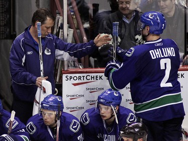 Canucks equipment manager Pat O'Neill (left) hands Mattias Ohlund a stick during a game in October 2008.