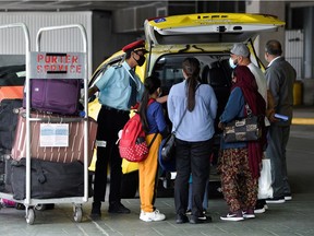 A porter loads the luggage of air travellers from New Delhi into a cab at Vancouver International Airport on Friday after Canada's government temporarily barred passenger flights from India and Pakistan for 30 days.