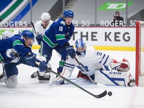 Vancouver Canucks' J.T. Miller, front left, puts a shot wide of the goal behind Toronto Maple Leafs goalie David Rittich as Vancouver's Jake Virtanen (18) watches during the second period.