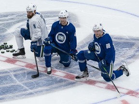 Jordie Benn #8, Elias Pettersson #40 and Nate Schmidt #88 of the Vancouver Canucks share a laugh while waiting for their turn during practice at the first day of the Vancouver Canucks NHL Training Camp at Rogers Arena on January 4, 2021. The Canucks are currently searching for a permanent practice facility.