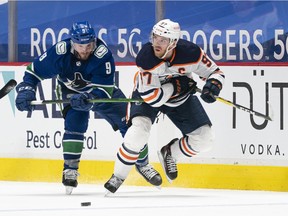 J.T. Miller of the Vancouver Canucks tries to check Connor McDavid of the Edmonton Oilers during the third period at Rogers Arena on Monday night.