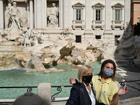 Tourists wearing a face pose by the Trevi Fountain in downtown Rome.