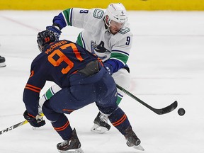 Vancouver Canucks forward J.T. Miller chips the puck past Oilers forward Connor McDavid in the second period.