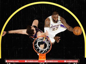 LeBron James of the Los Angeles Lakers attempts a lay-up past Dario Saric of the Phoenix Suns at Phoenix Suns Arena on May 23, 2021 in Phoenix.