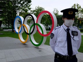 Security guards keep watch next to the Olympic Rings while people take part in a protest against the hosting of the 2020 Tokyo Olympic Games on May 18, 2021.