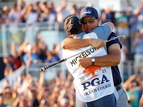 Phil Mickelson hugs caddie Tim Mickelson after he putts out on the 18th hole and wins the PGA Championship golf tournament.