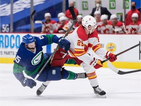 Calgary Flames' Dillon Dube (29) checks Vancouver Canucks' Matthew Highmore (15) during the first period.