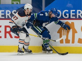 Edmonton Oilers forward Connor McDavid (97) checks Vancouver Canucks forward J.T. Miller (9)  in the second period at Rogers Arena.
