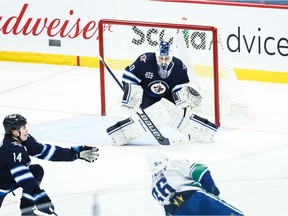 Winnipeg Jets goalie Laurent Brossoit (30) makes a save on a shot by Vancouver Canucks forward Nils Hoglander, who scored two goals in a 3-1 win on Monday night.