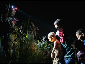 A member of the National Guard addresses an immigrant family seeking asylum as they arrive on U.S. soil after crossing the Rio Grande on June 19, 2021 in Roma, Texas. A surge of mostly Central American immigrants crossing into the United States has challenged U.S. immigration agencies along the U.S. Southern border.