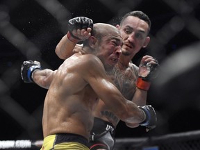 Max Holloway, right, punches Jose Aldo, of Brazil, during the third round of a UFC 218 featherweight mixed martial arts bout, early Sunday, Dec. 3, 2017, in Detroit.