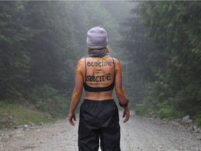 A woman stands near a blockade of protesters against old growth timber logging in the Fairy Creek area of Vancouver Island, near Port Renfrew on May 24, 2021.