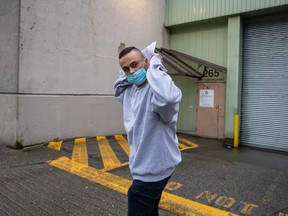 Mohammad Movassaghi tries to hide his face with a copy of his release order as he leaves Vancouver Police Department jail in Vancouver on Sunday, January 31, 2021. Police arrested a man who allegedly operated a makeshift nightclub at his Vancouver penthouse and issued fines against him and his suspected guests totalling more than $17,000.