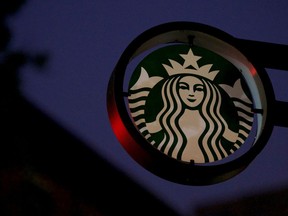 Traffic lights illuminate a Starbucks sign.