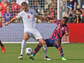 Kellyn Acosta #23 of the United States reaches in for the ball against Liam Fraser #8 of Canada during the second half of the 2021 CONCACAF Gold Cup match at Children's Mercy Park on July 18, 2021 in Kansas City, Kansas.