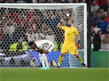 Marcus Rashford of England looks dejected after hitting the post in their team's third penalty as Gianluigi Donnarumma of Italy celebrates in a penalty shoot out during the UEFA Euro 2020 Championship Final between Italy and England at Wembley Stadium on July 11, 2021 in London, England.