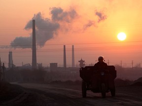 A man drives his tractor past a coking factory at sunrise in Linfen, Shanxi Province, China, in a file photo from December 2009. China’s contribution to the planet’s carbon load has doubled since 2001, after having tripled in the previous decade.