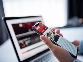 Online news on a smartphone and laptop, Woman reading news or articles in a mobile phone screen application at home. Newspaper and portal on internet.